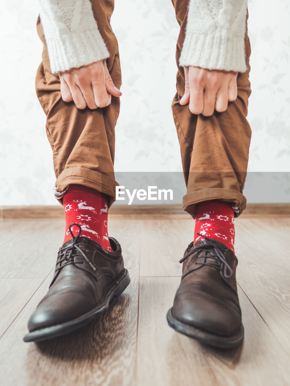 Young man shows bright red socks with reindeers on them. casual outfit for new year and christmas.