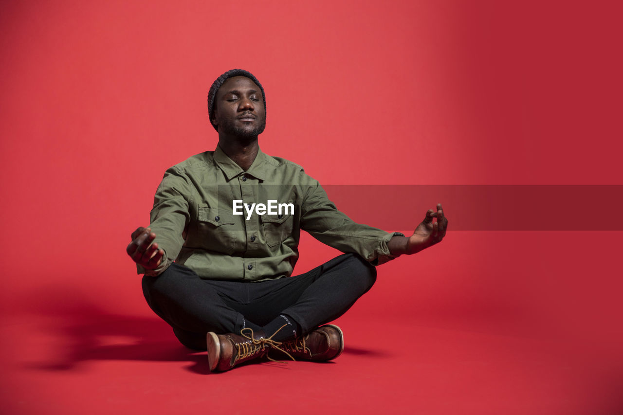 Young black man meditating on studio floor