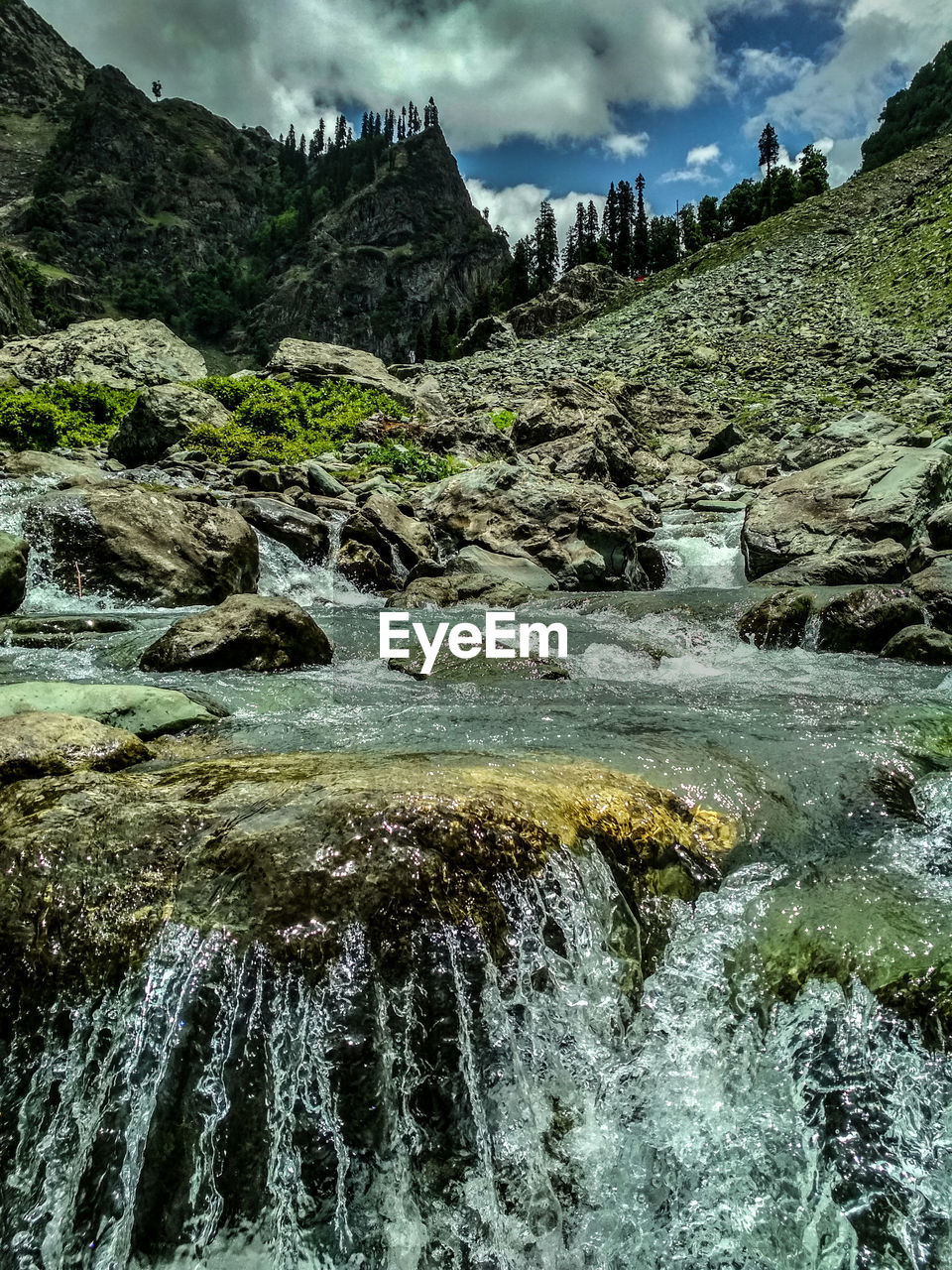 Water flowing through rocks against sky