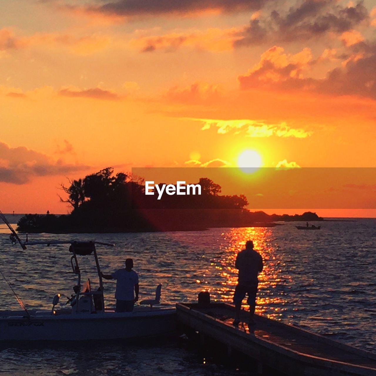 Men standing on boat at sunset