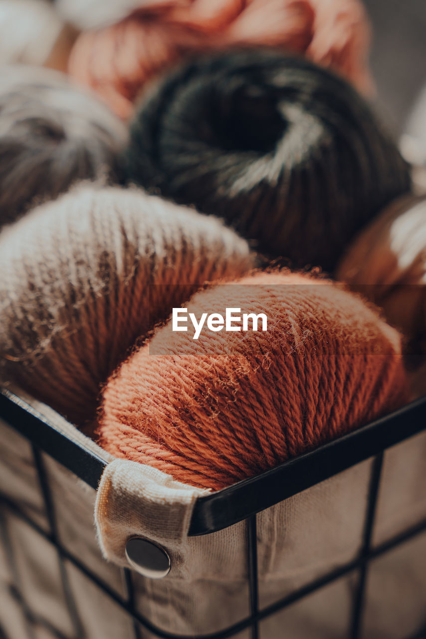 Close up of earth coloured merino wool yarn inside a basket, sunlight from the window on it.