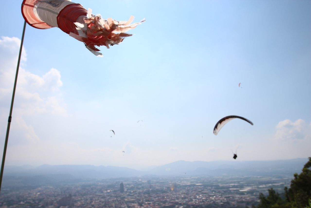 Paragliding over cityscape with windsock blowing in foreground