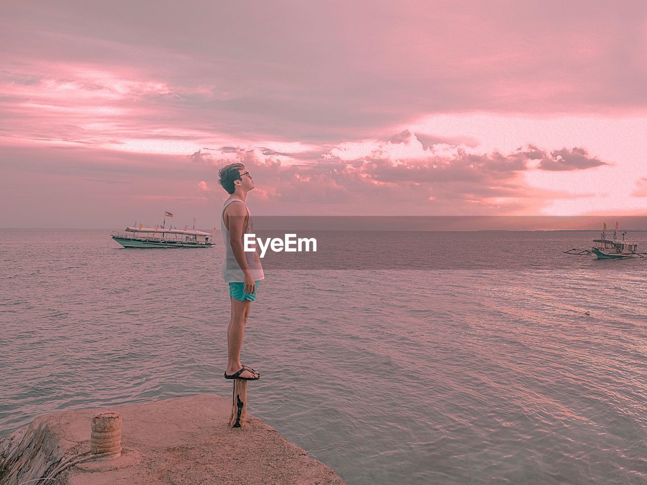 WOMAN STANDING ON BEACH DURING SUNSET