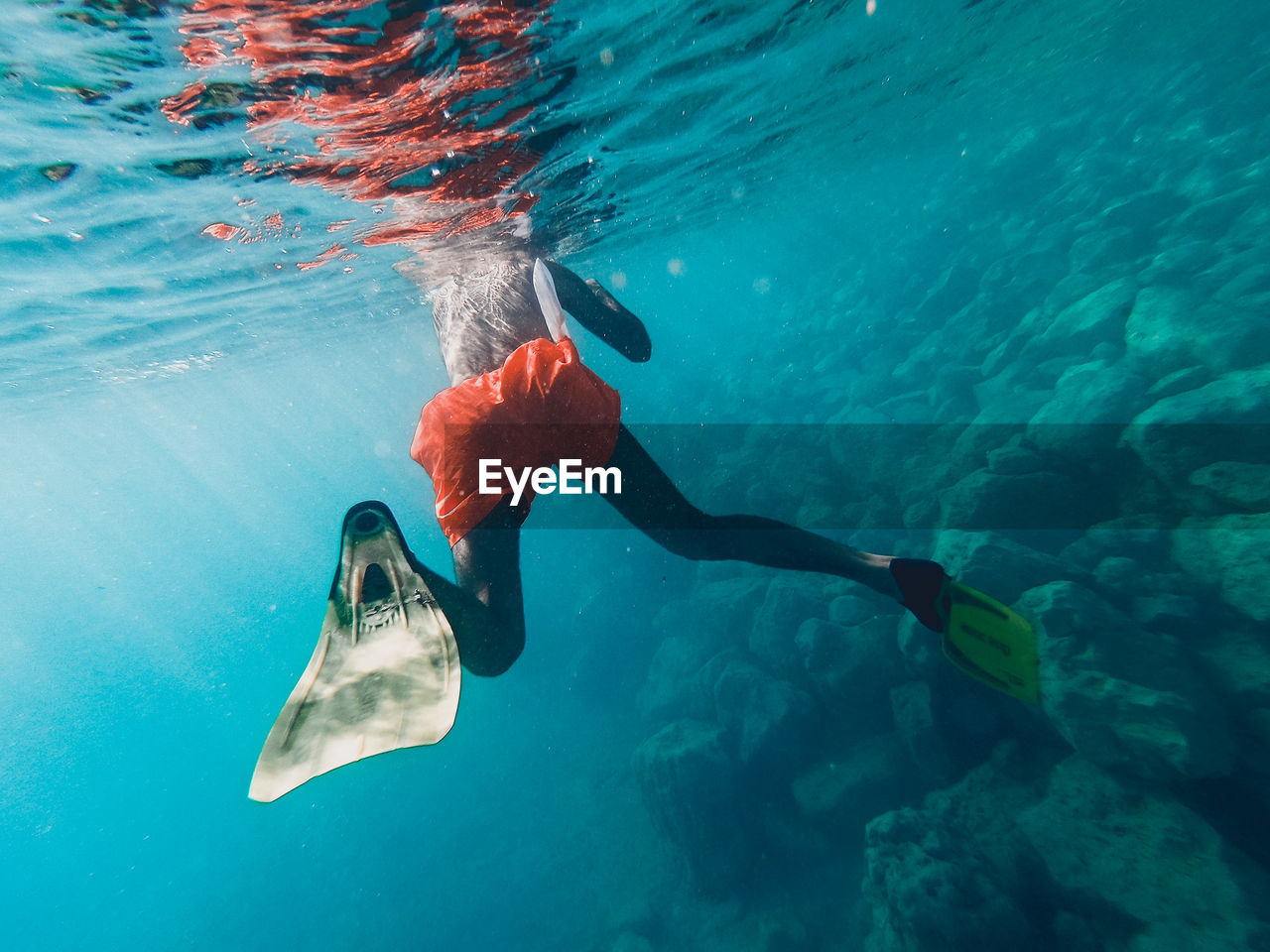 Low section of shirtless man swimming in sea