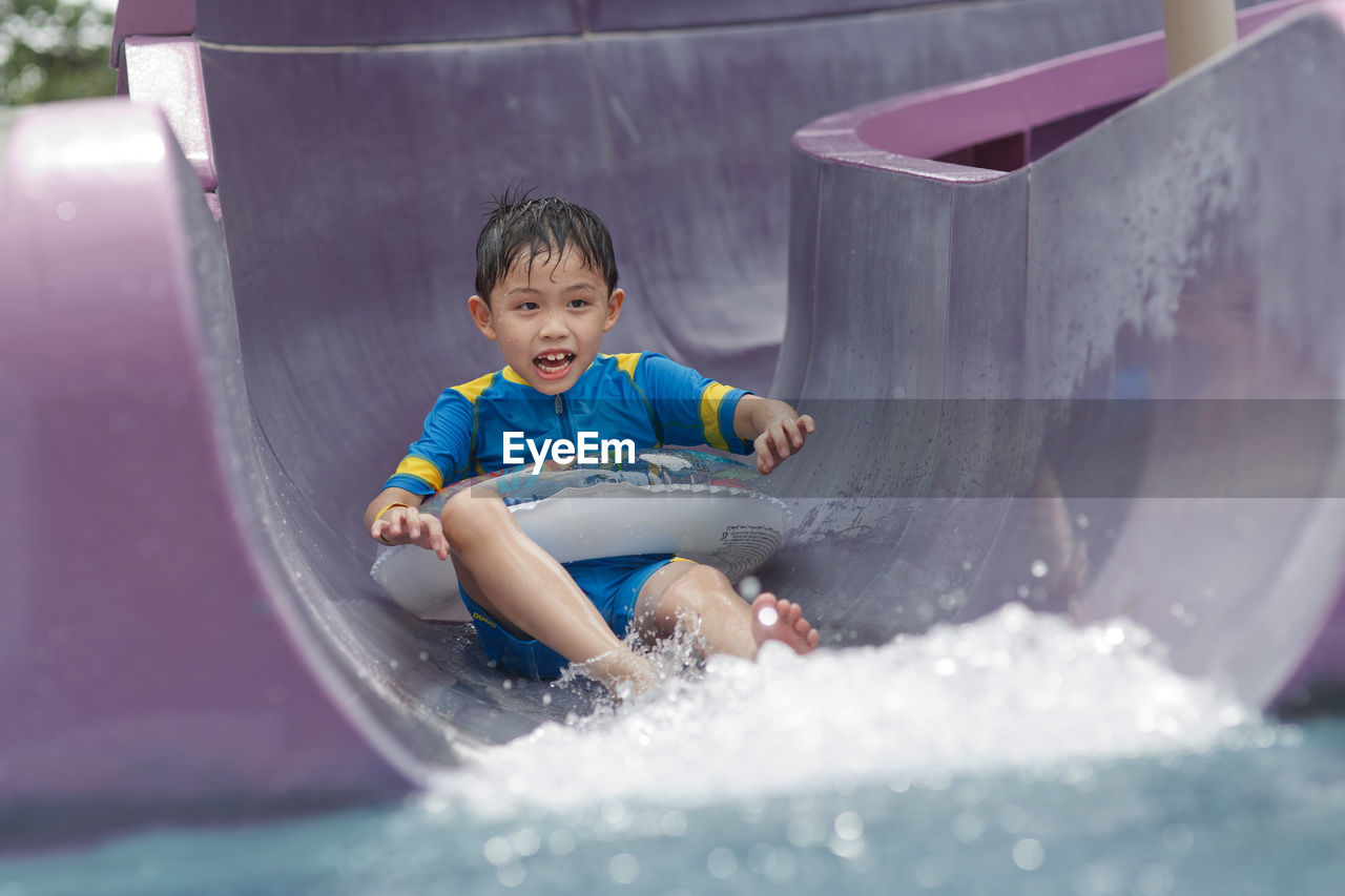 Boy sliding down in water slide at water park