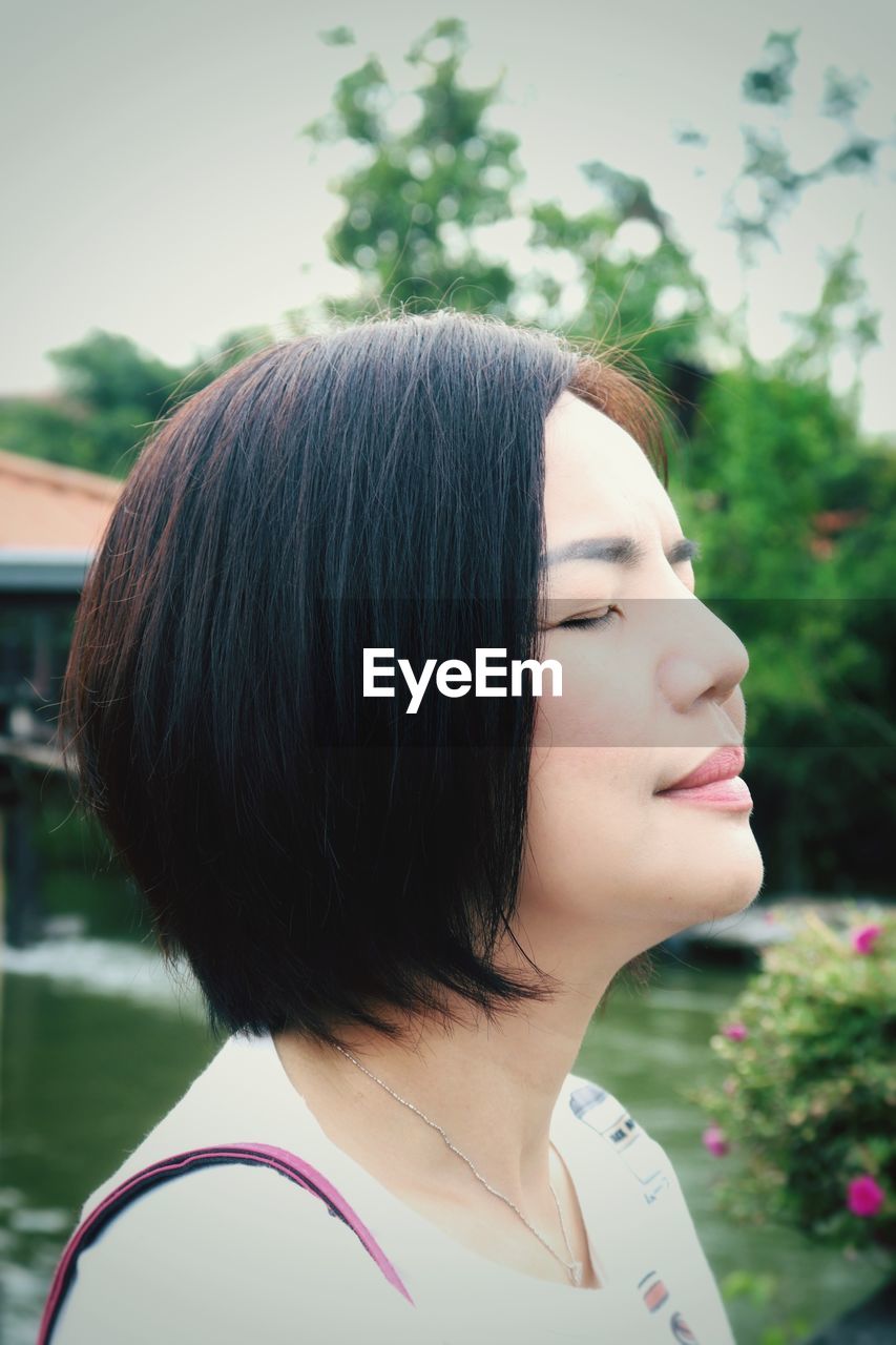 Close-up of smiling woman with eyes closed outdoors