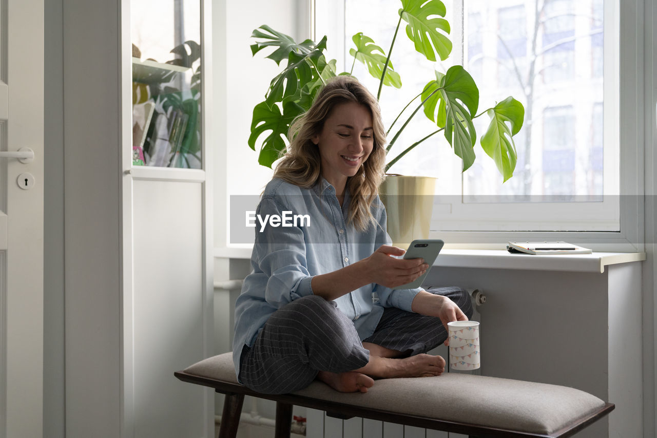 Woman using phone while sitting at home