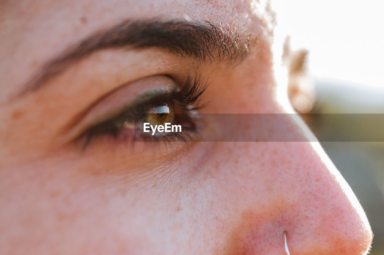 Closeup crop green eyes of serene female standing in summer nature on sunny day