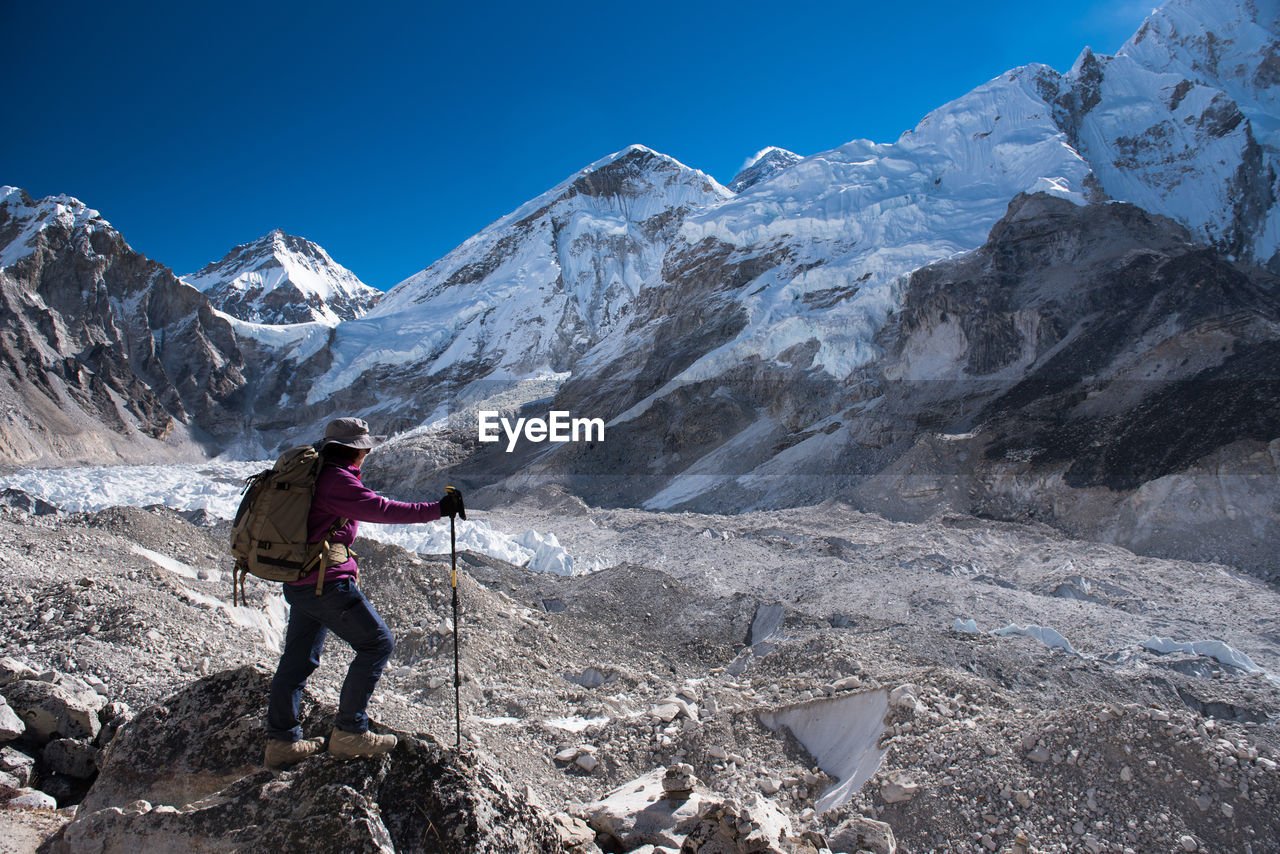Hiker standing on rock against mountain range 