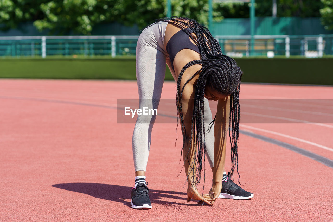 African american woman with long braids bends down doing effective exercise for stretching body