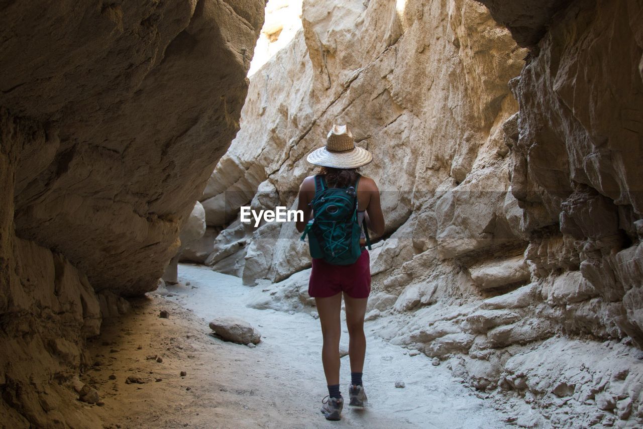 Rear view of woman walking amidst rock formation