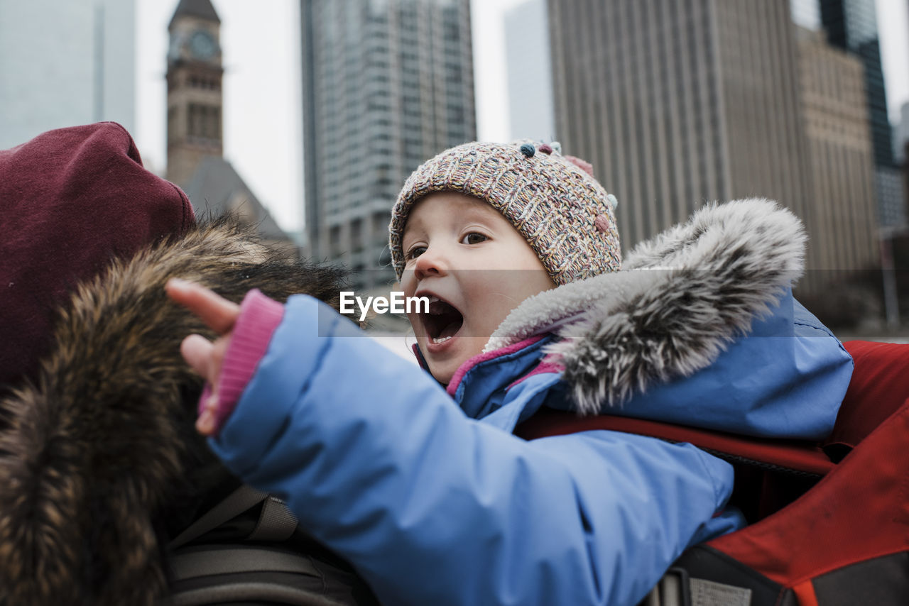 Side view of father piggybacking daughter while walking on city street