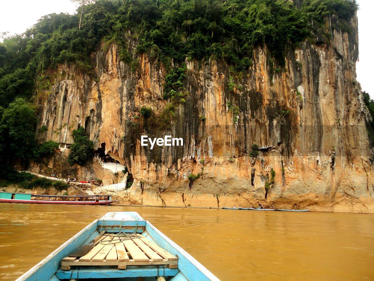 Boat on mekong river against pak ou caves