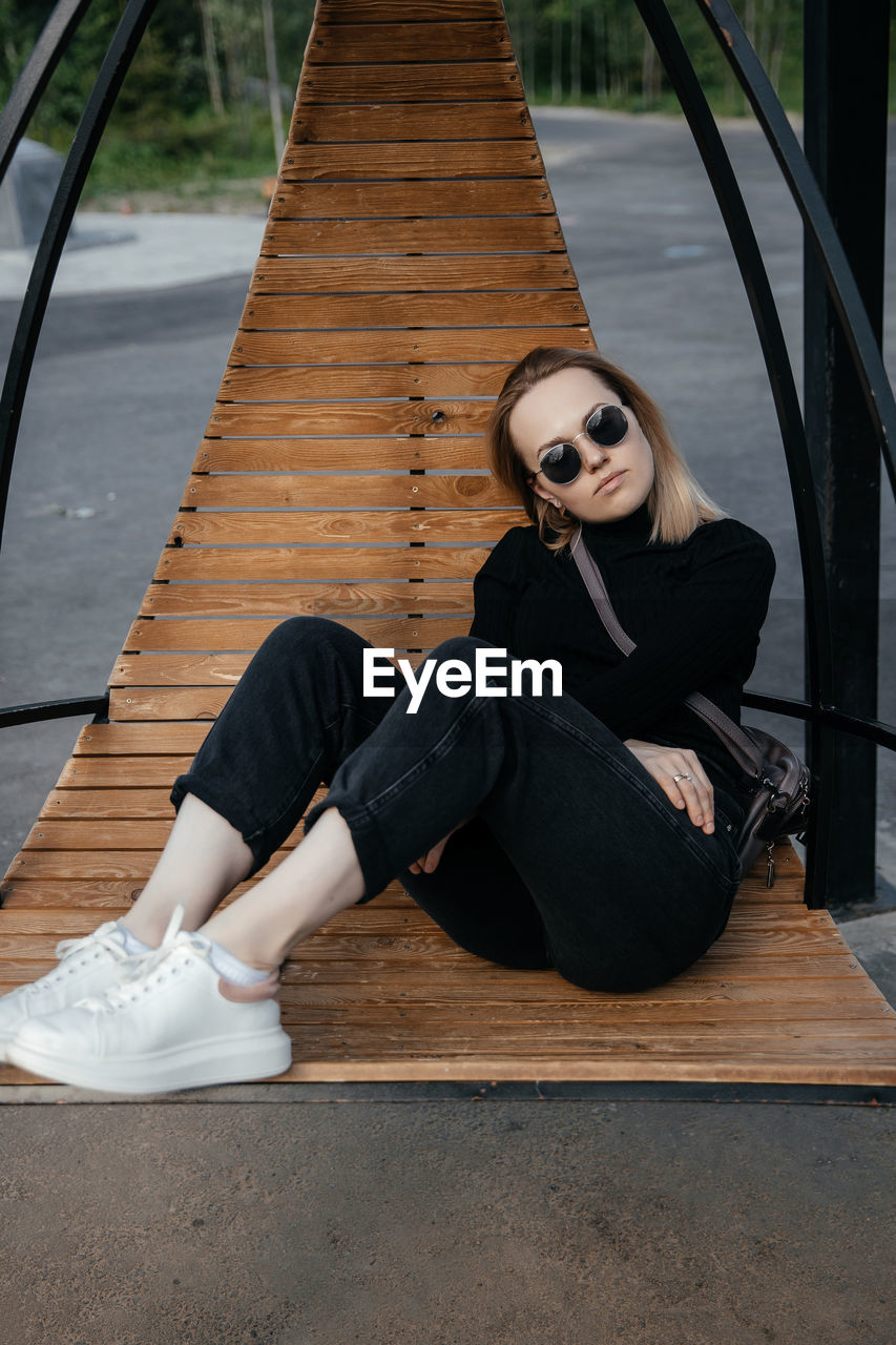 Young beautiful white girl is sitting on a park bench. cute female lifestyle, portrait