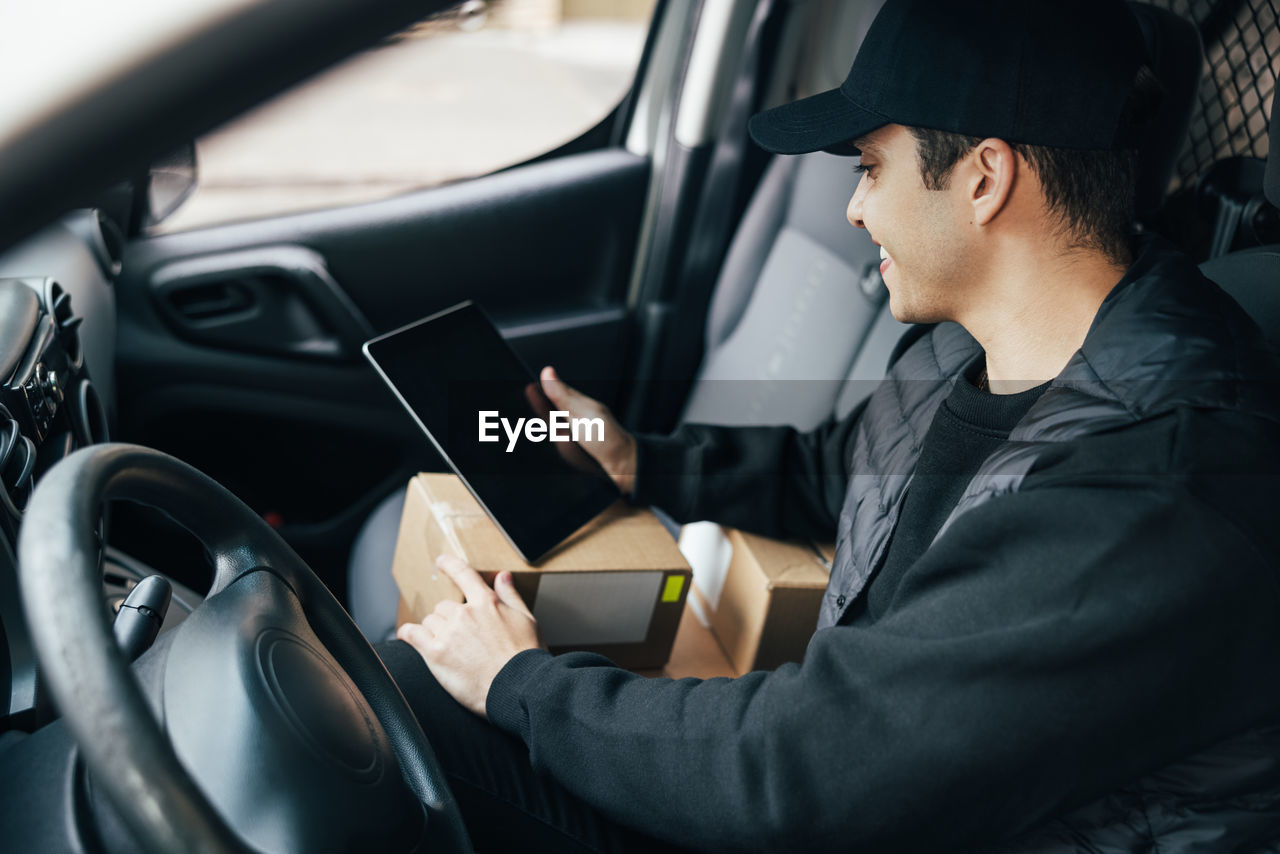 Midsection of man using mobile phone while sitting in car