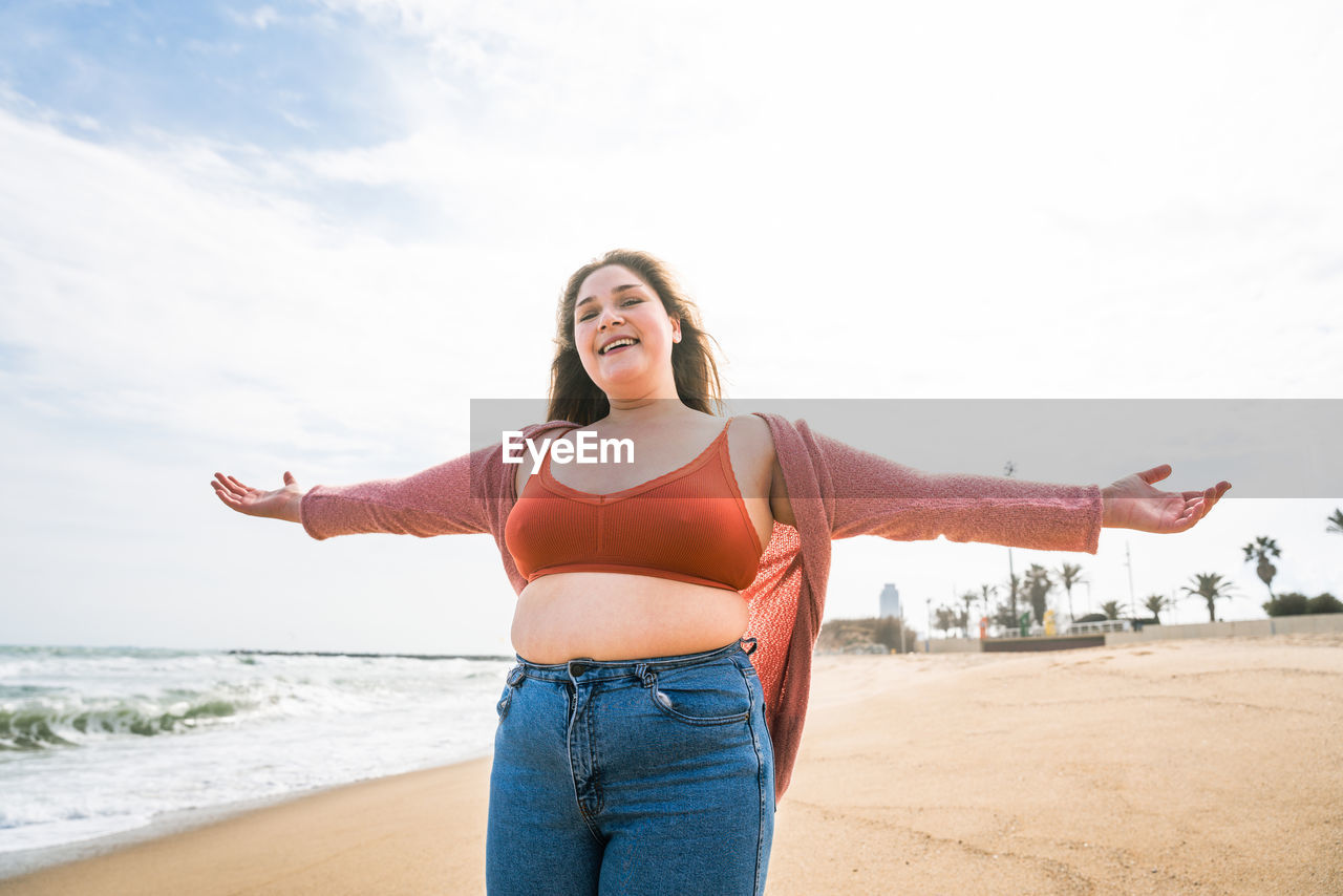 Woman standing at beach against sky