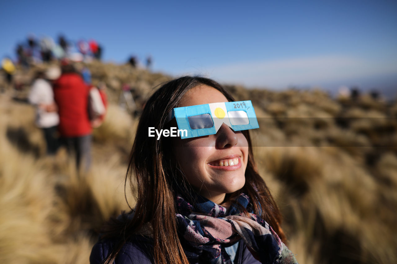 Smiling teenage girl wearing 3-d glasses outdoors