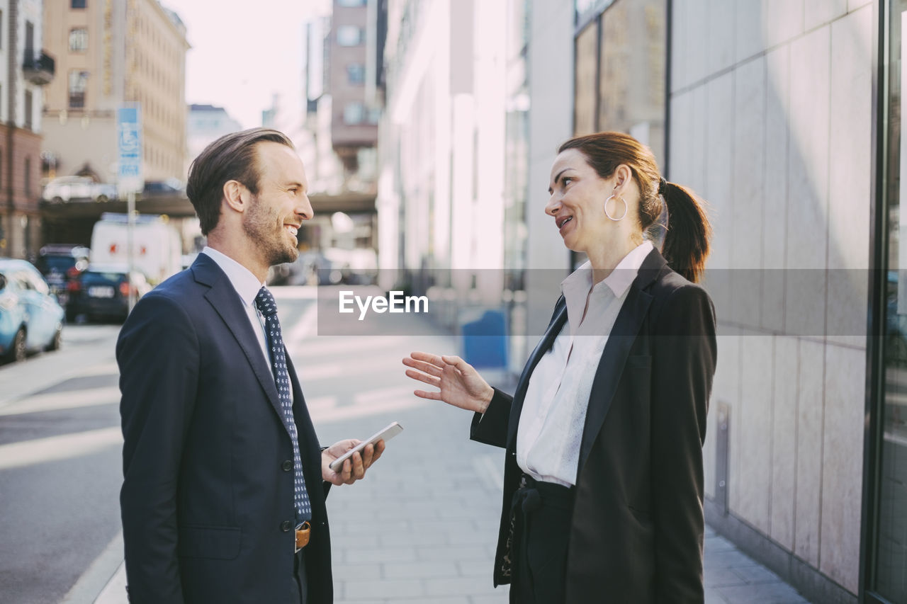 Smiling businesswoman talking to coworker in city