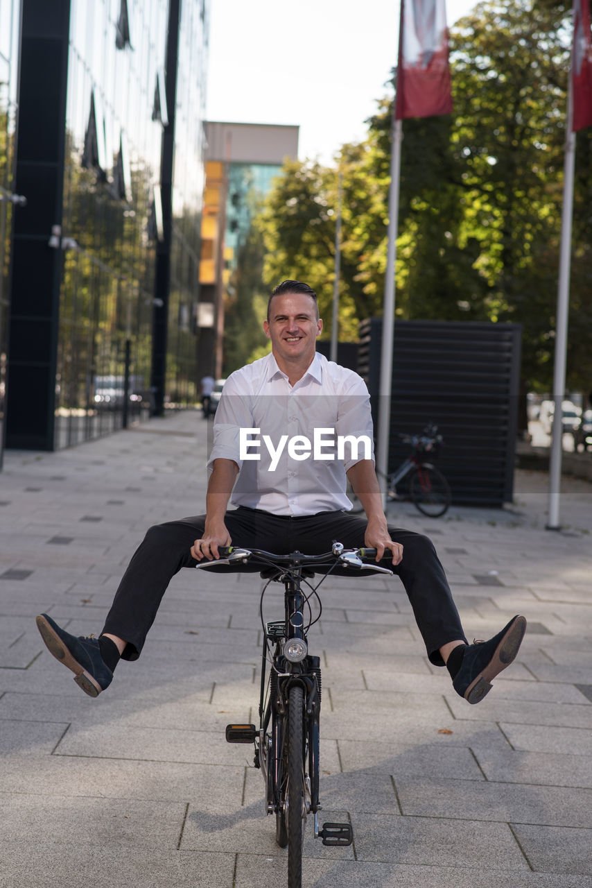 Portrait of smiling man riding bicycle on street in city