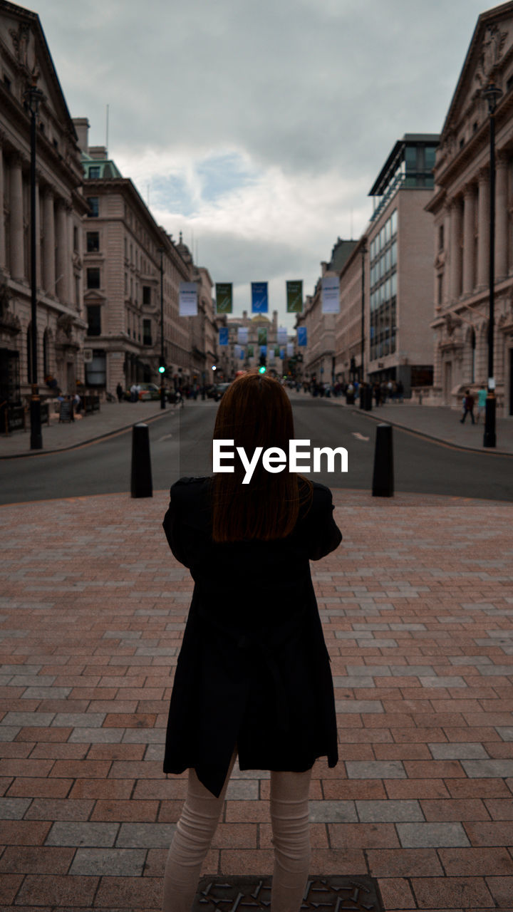 Rear view of woman standing on footpath in city of london 