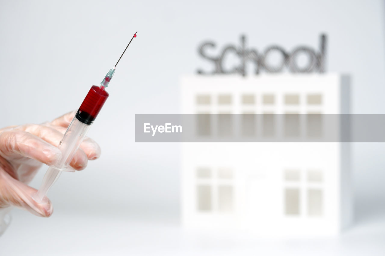 CLOSE-UP OF HAND HOLDING RED BELL WITH EYEGLASSES