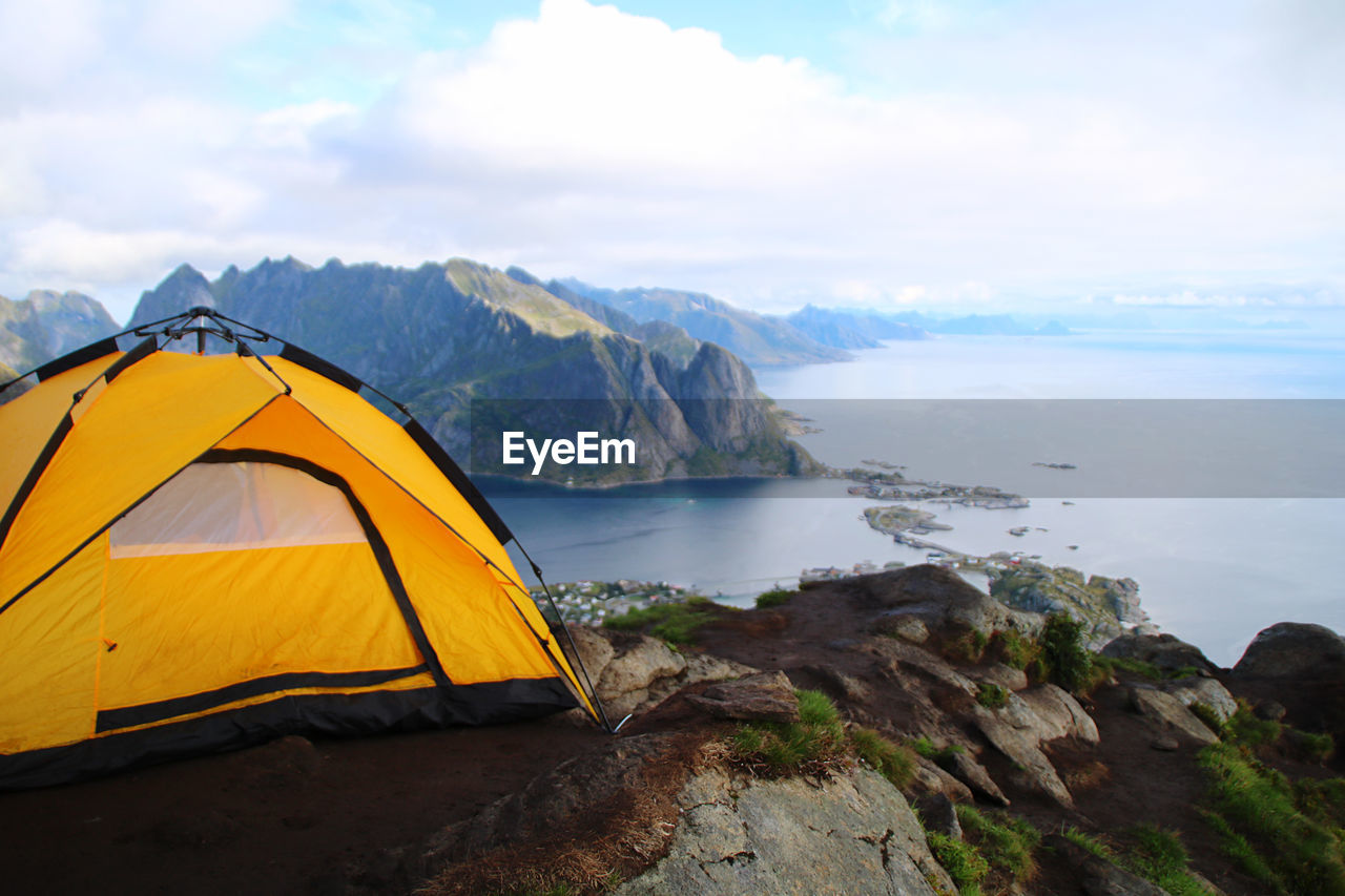 Scenic view of sea and mountains with camping tent on top of the world