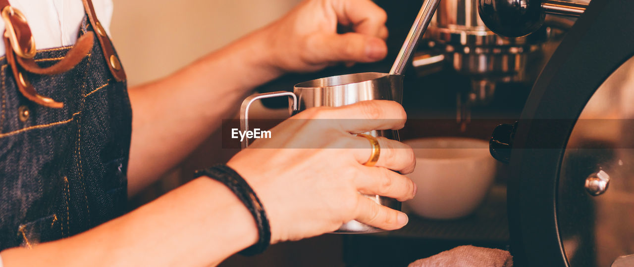 Midsection of barista making coffee in cafe