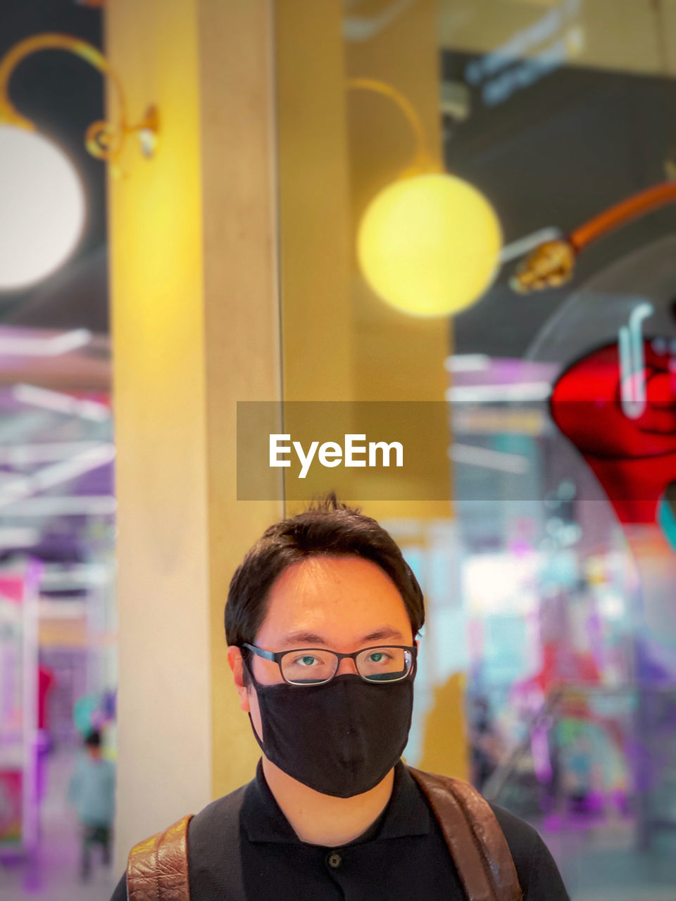 Portrait of young man in eyeglasses against lights, neon lights and reflection.