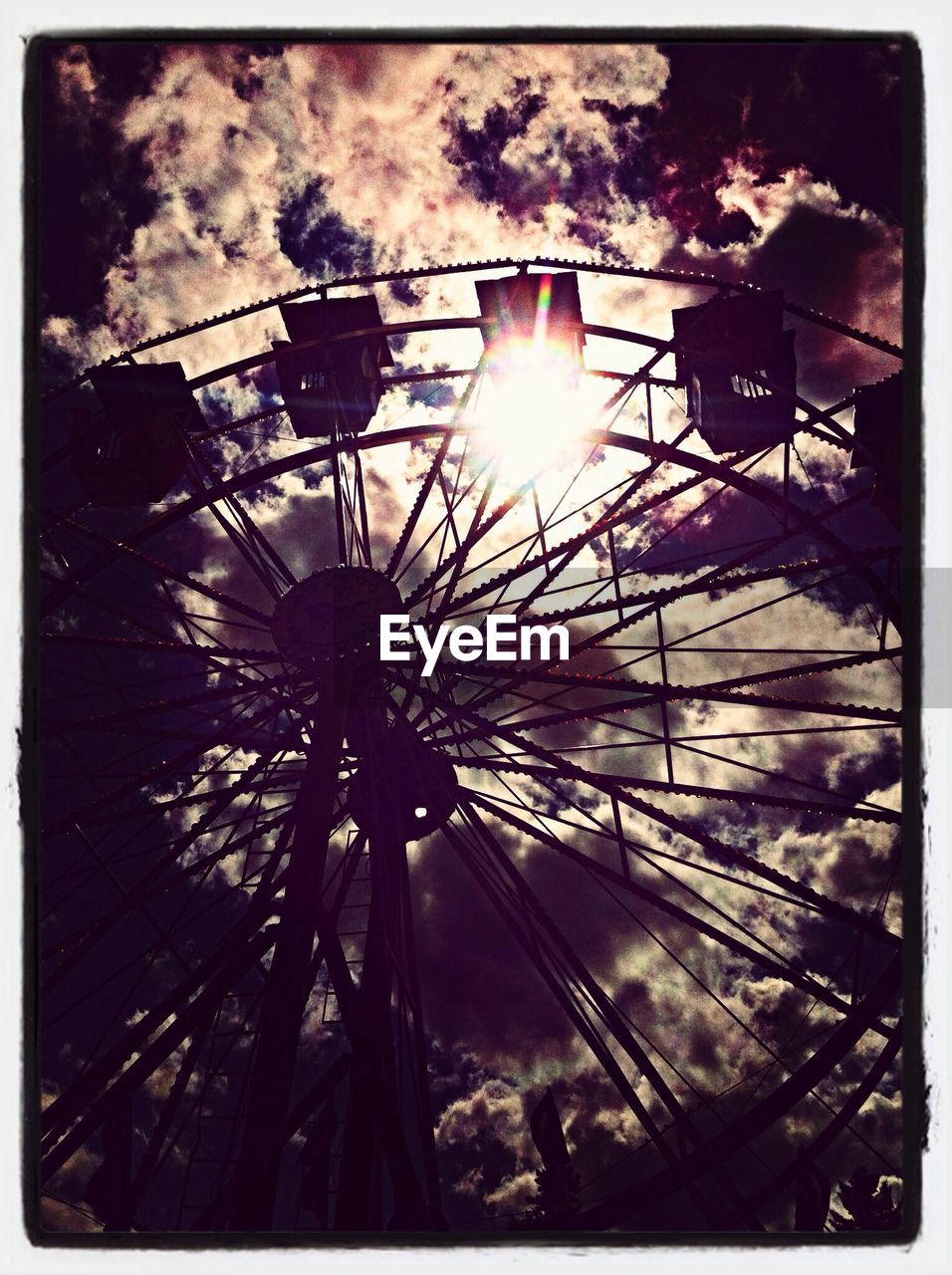 Low angle view of silhouette ferris wheel against cloudy sky