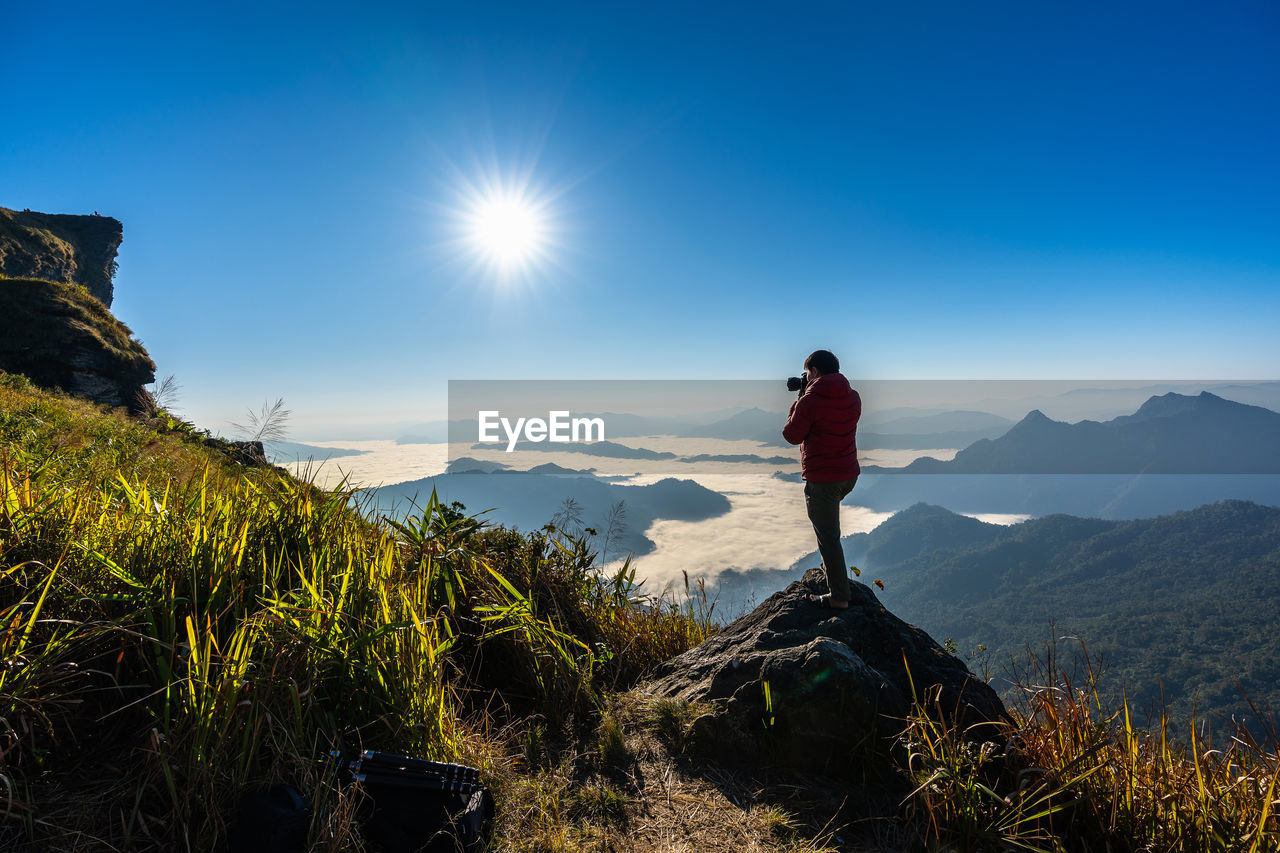 Man photographing on mountain against sky