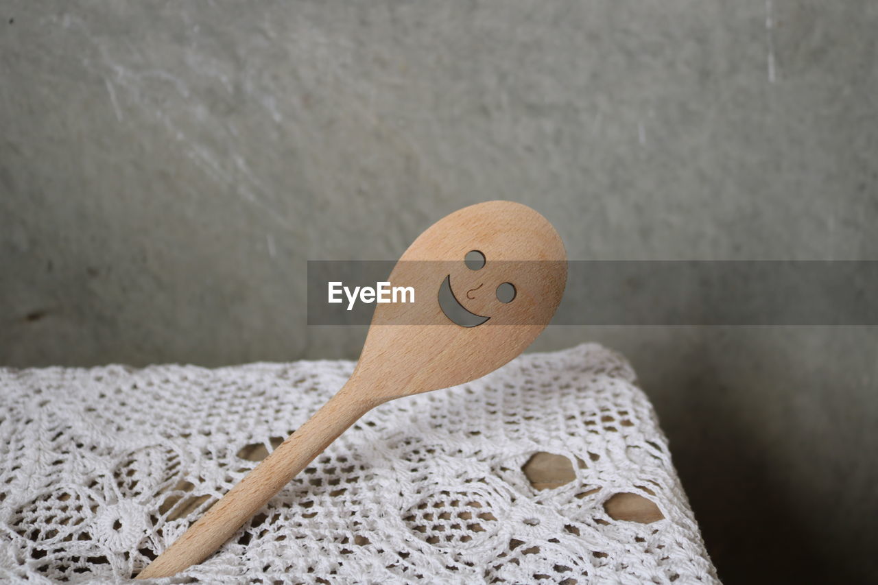 Close-up of smiley face on wooden spoon against wall