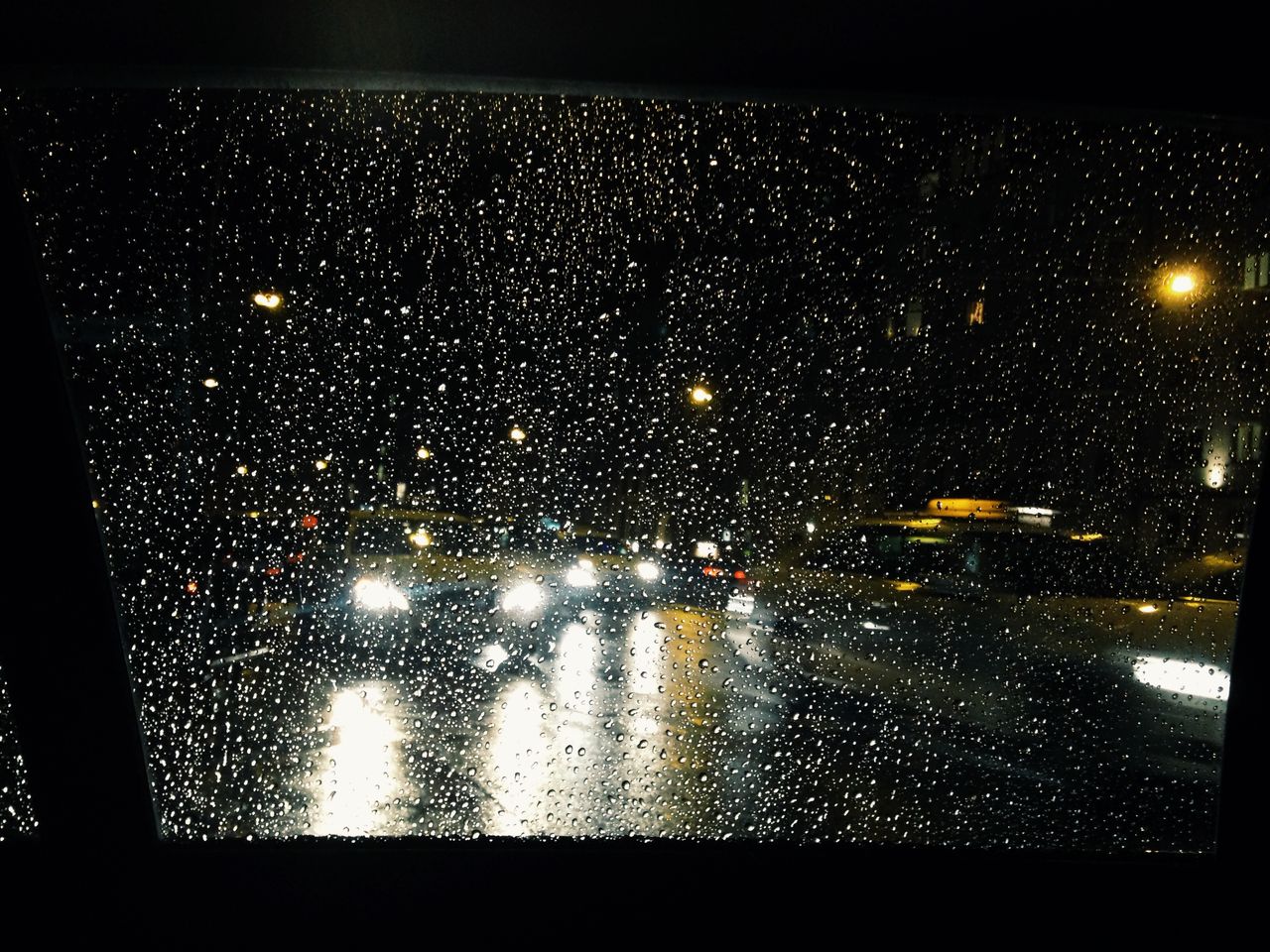 Cars' headlights behind wet glass