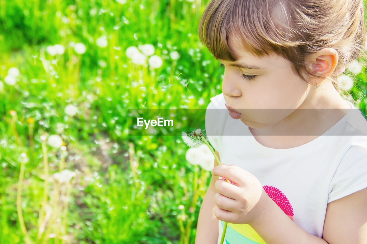 close-up of girl blowing bubbles while standing against trees