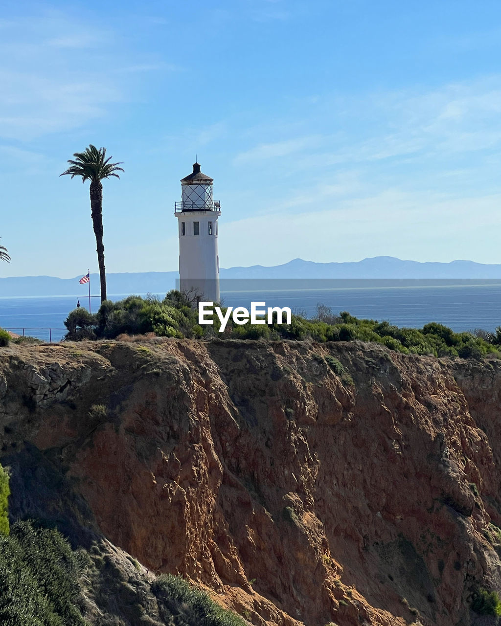 lighthouse, guidance, tower, coast, sky, sea, architecture, security, built structure, water, protection, building, nature, beach, building exterior, land, travel destinations, no people, travel, rock, scenics - nature, cliff, ocean, day, plant, blue, coastline, cove, outdoors, environment, terrain, cloud, landscape, beauty in nature, tourism, non-urban scene, tranquility, tree, horizon