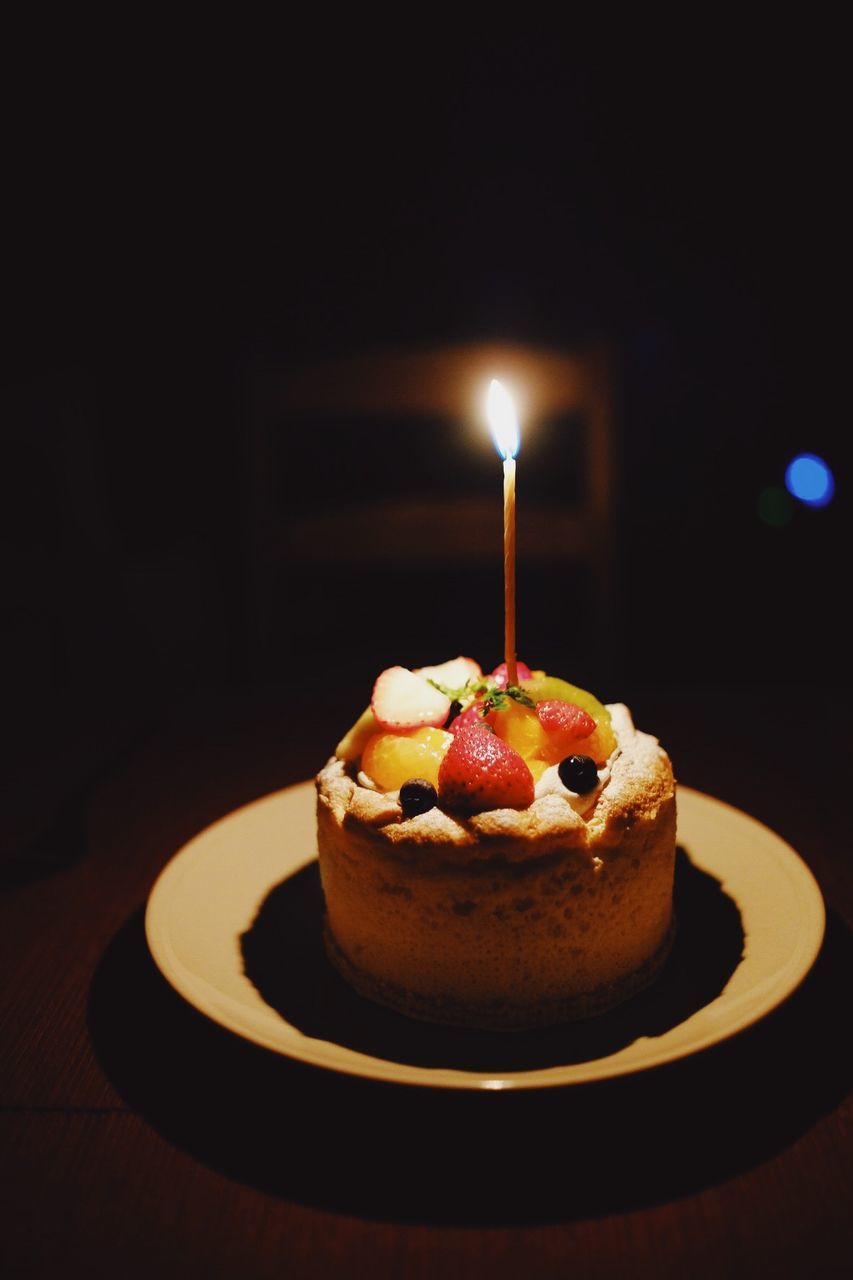 CLOSE-UP OF CAKE WITH ILLUMINATED CANDLES