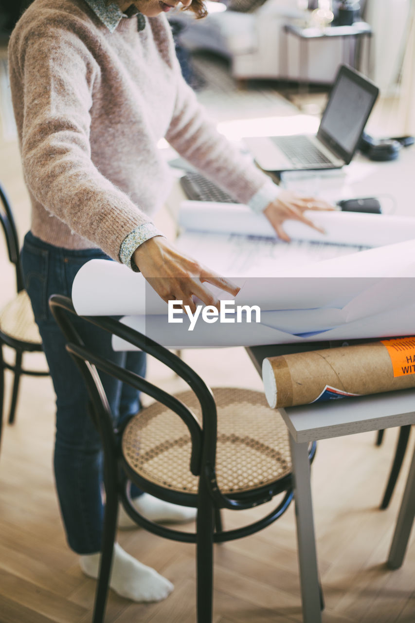 Woman working at home looking at blueprints