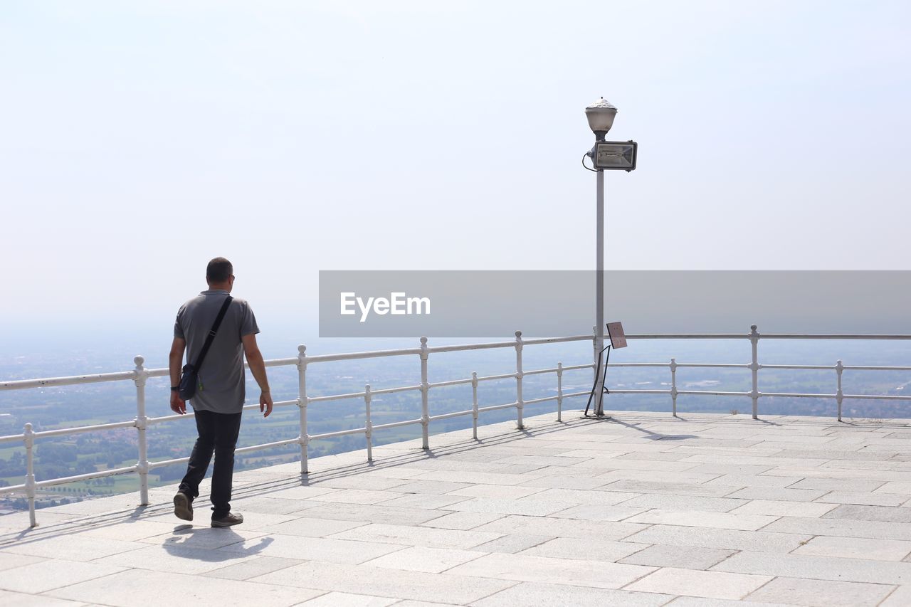 Man walking at observation point against sky