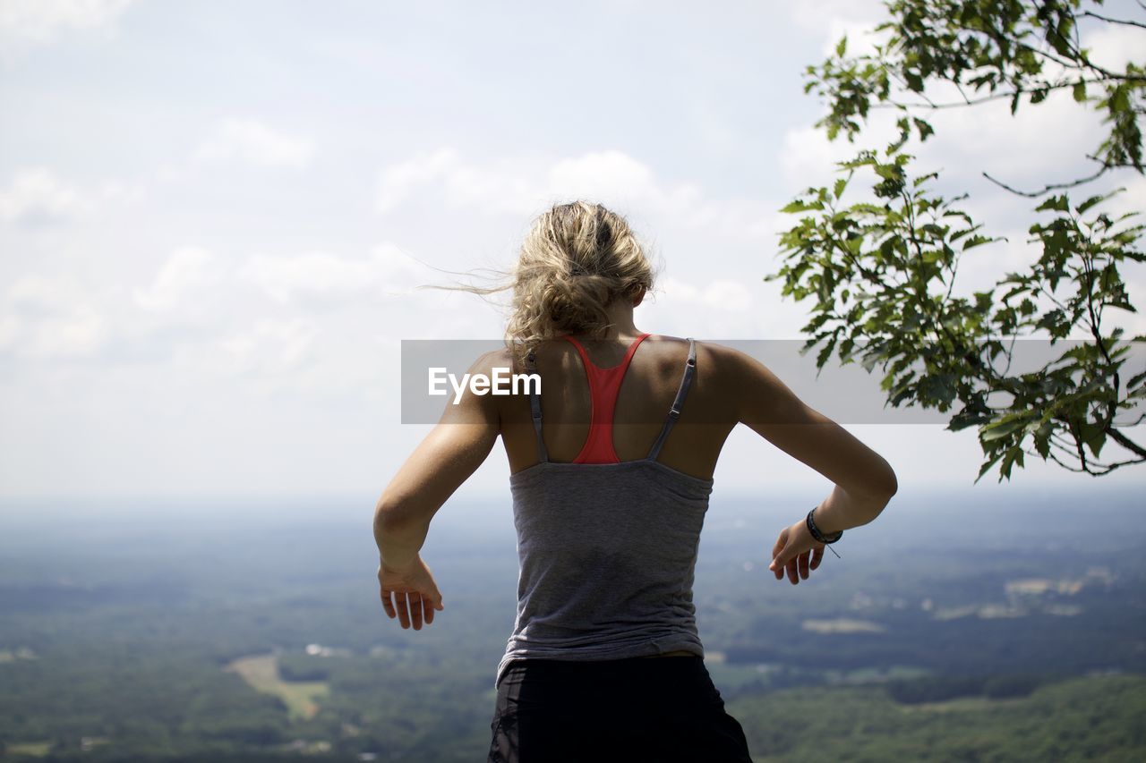 Inspiring rear view of woman standing against sky hope on mountain 