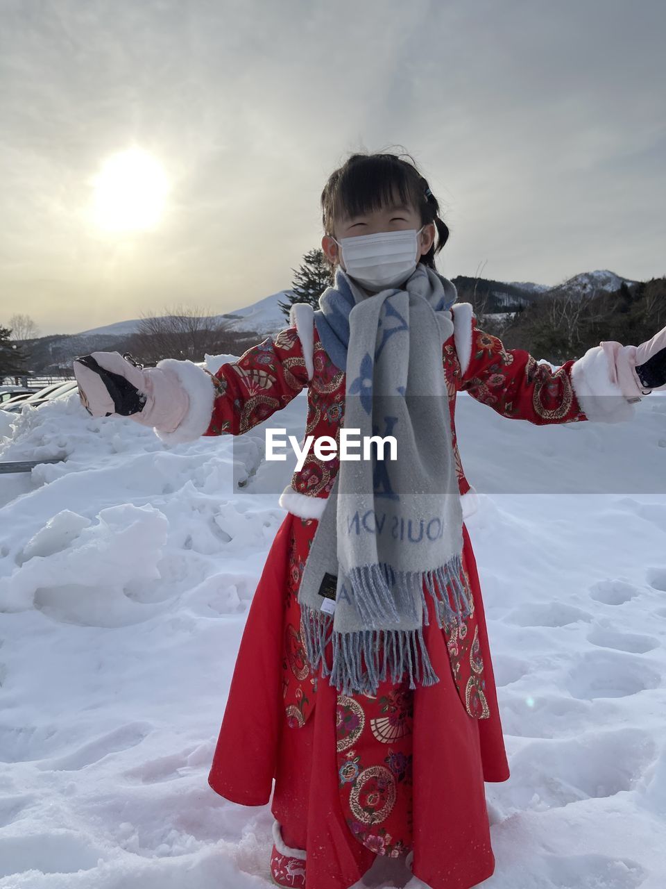 Girl standing on snow covered land against sky