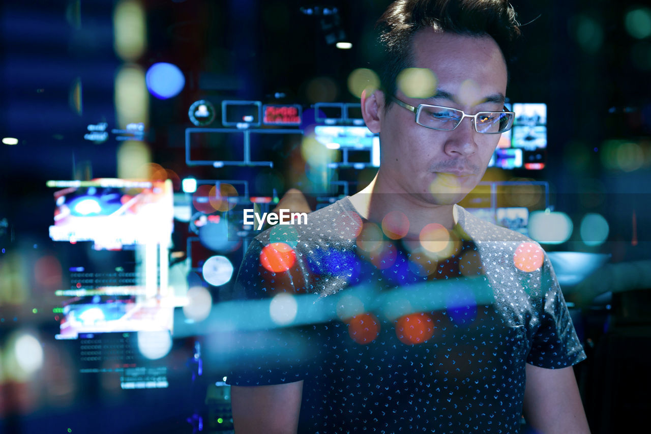 Portrait of young man standing at illuminated nightclub