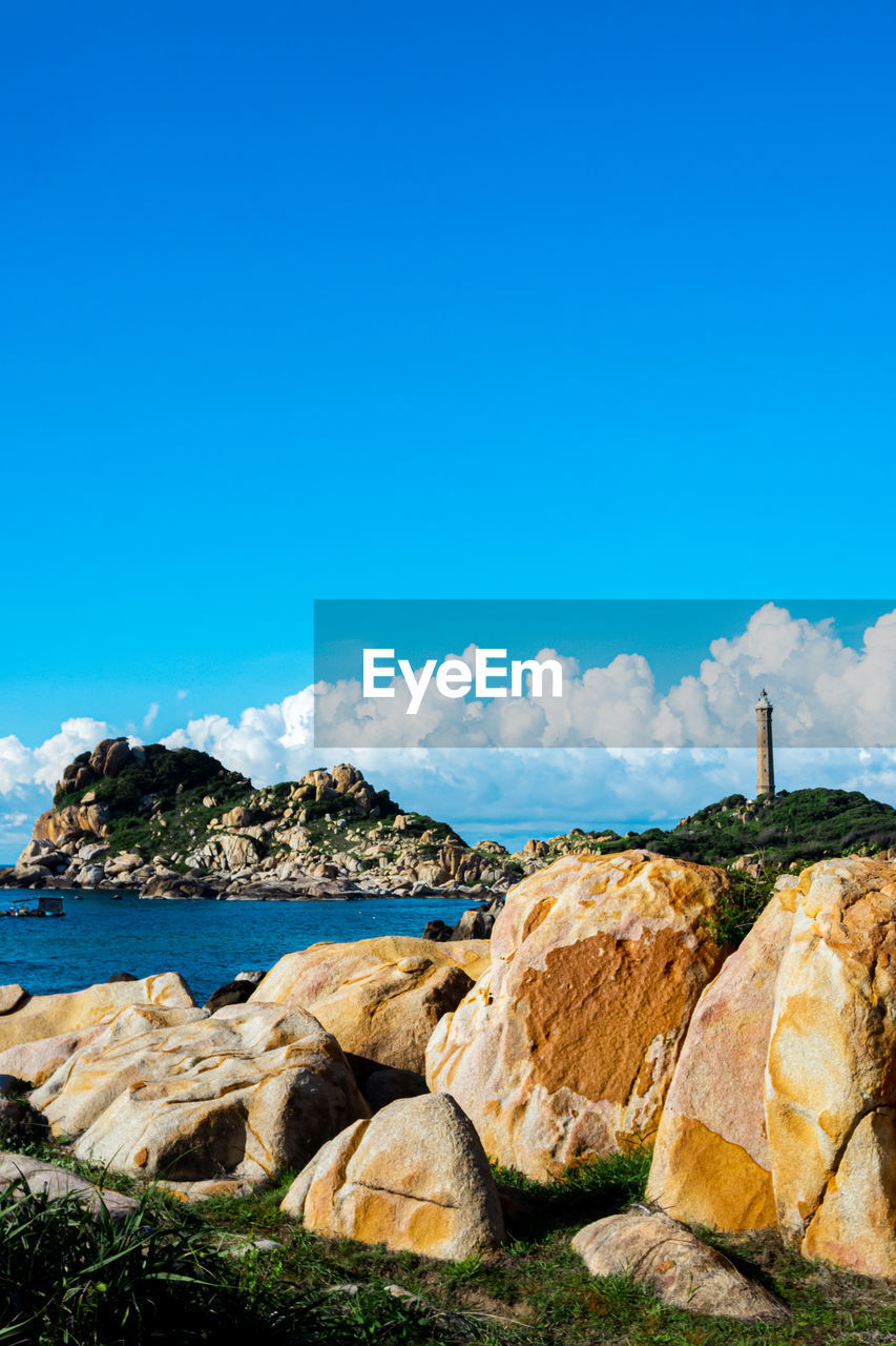 Rocks by sea against blue sky