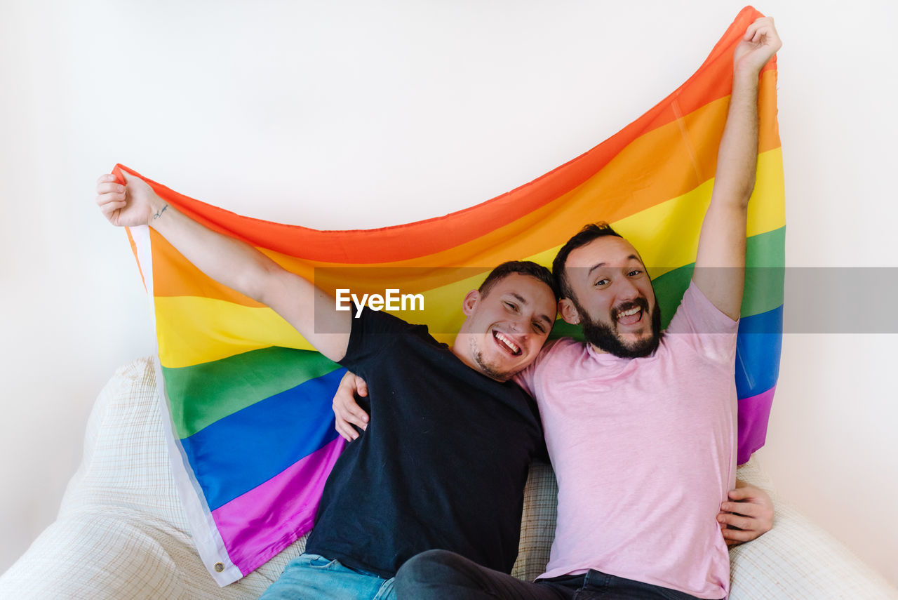 Two homosexual men holding lgbtq flag.