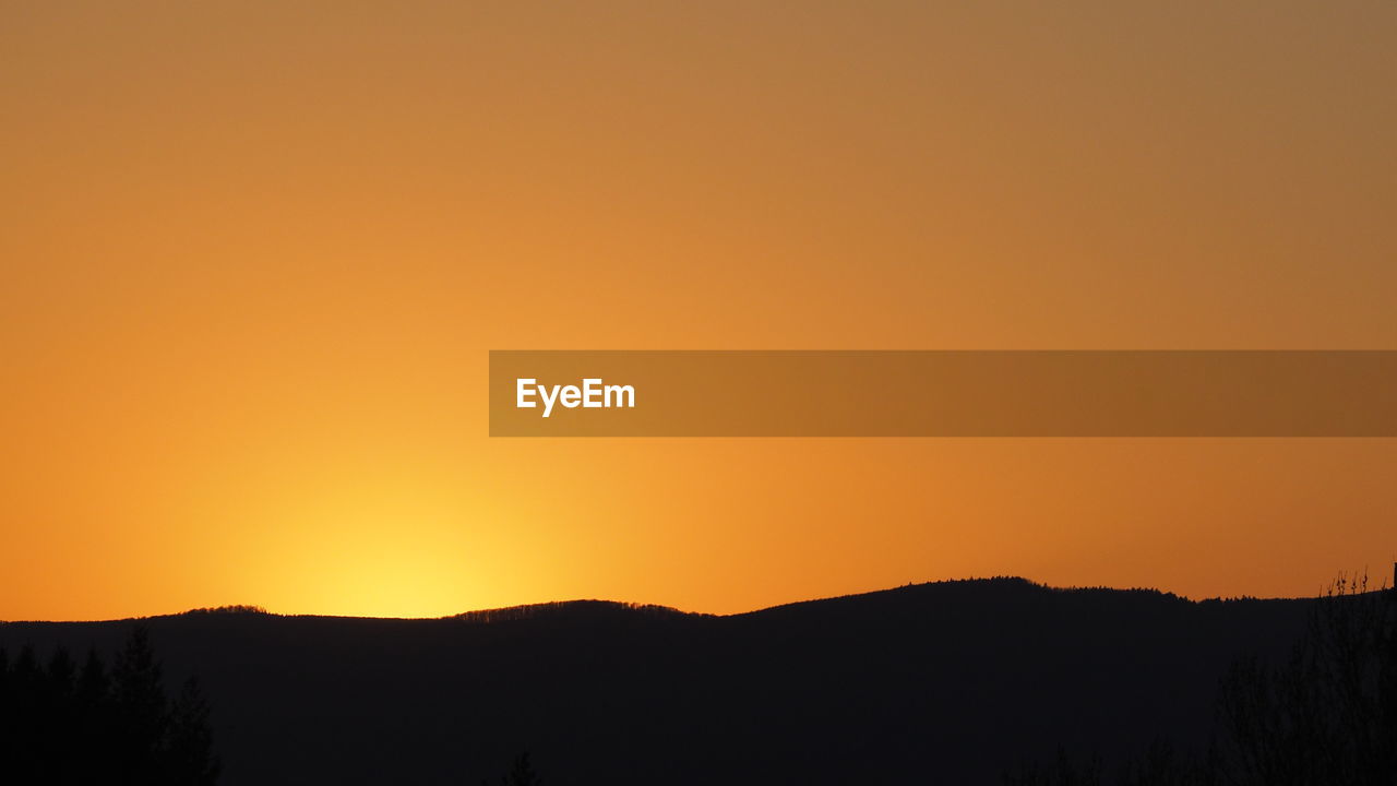 Scenic view of silhouette mountains against orange sky