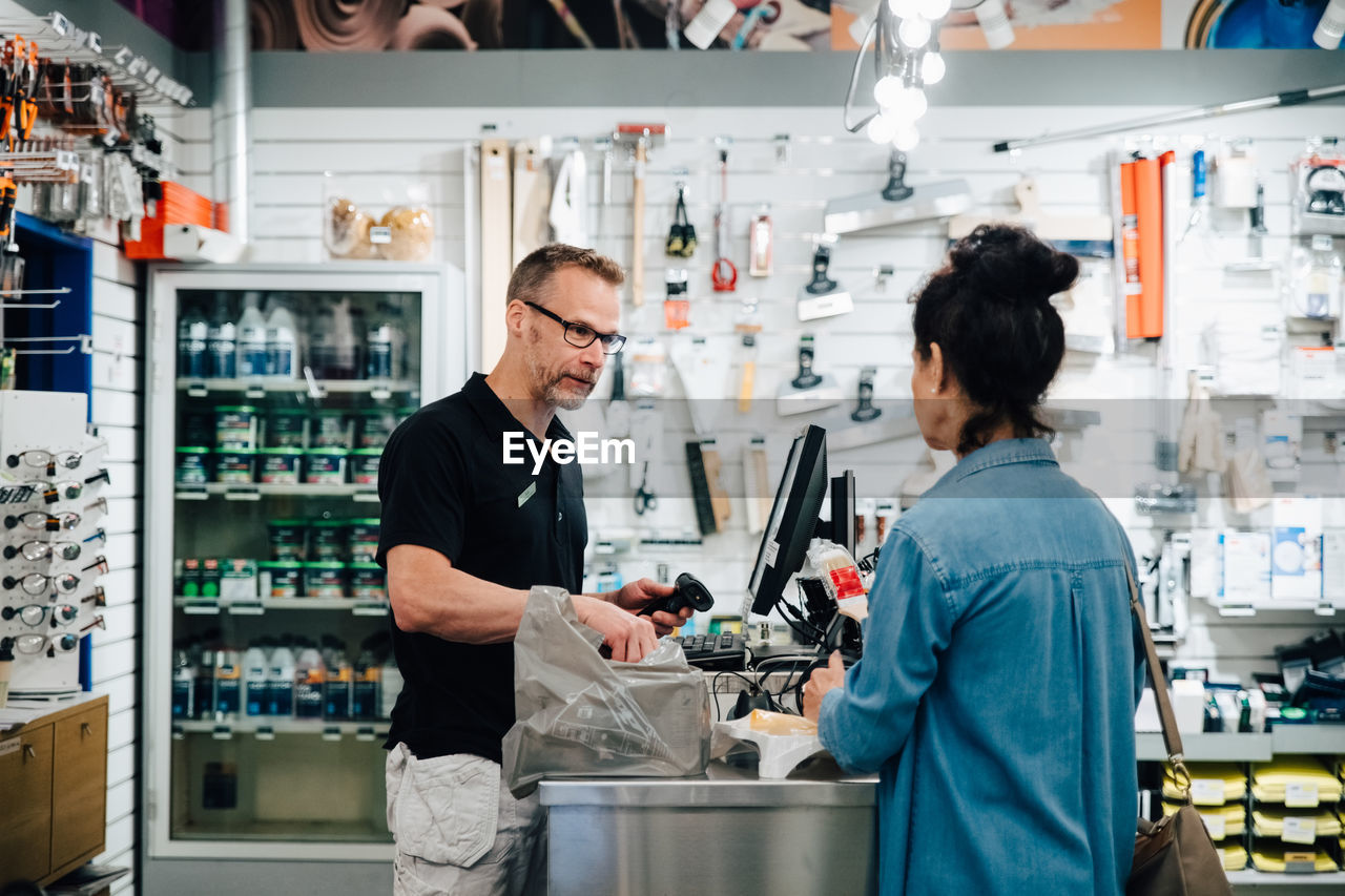 Female customer talking with shop owner at checkout counter in store