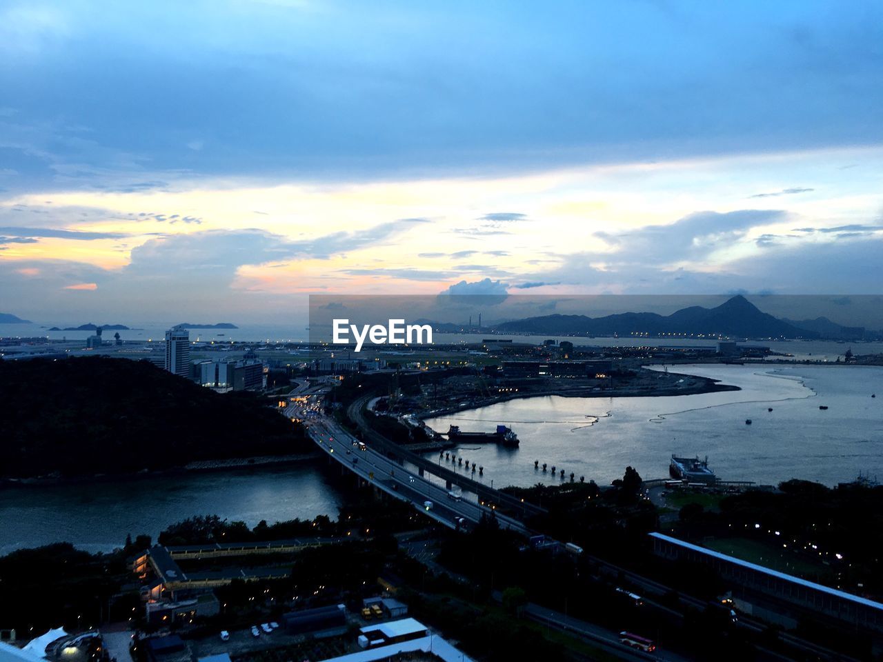 VIEW OF ILLUMINATED CITYSCAPE AGAINST CLOUDY SKY