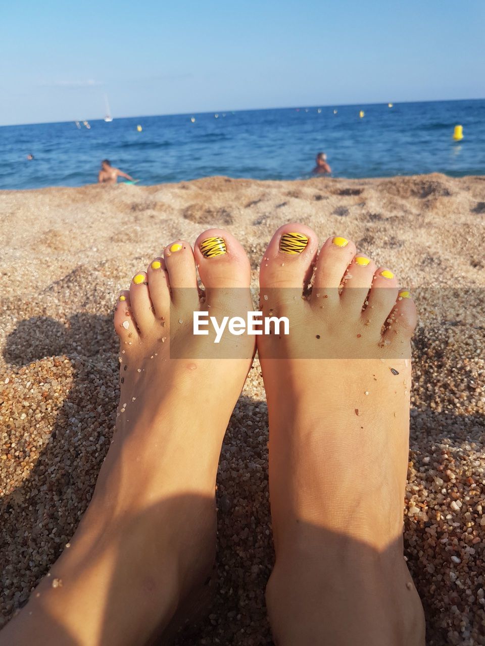 Low section of woman with nail polish at beach
