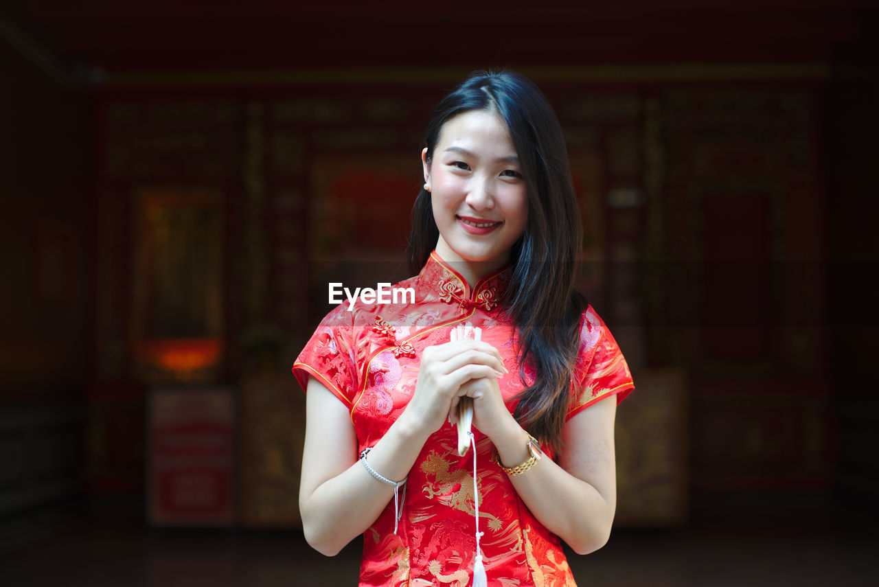 Portrait of young woman wearing red traditional clothing while standing outdoors