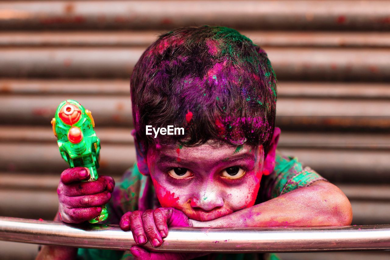 Portrait of boy covered with colors holding holi gun