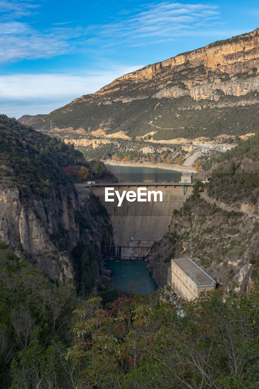 Water dam with hydroelectric installations between mountains in autumn
