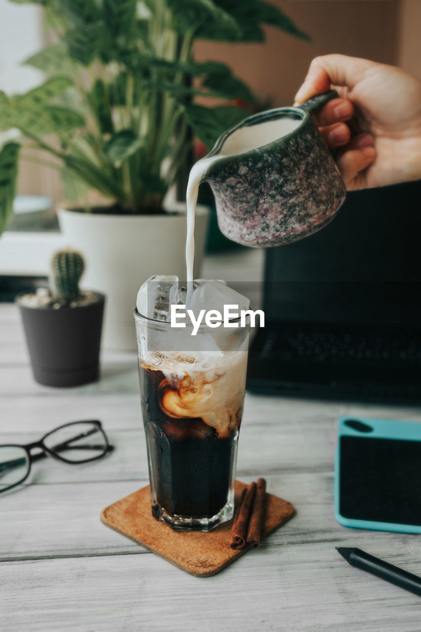 Milk is poured into the ice cold coffee cup